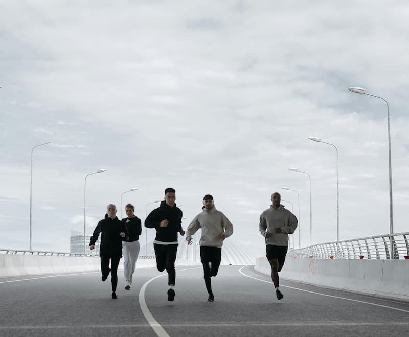 Four runners on an open road under a cloudy sky