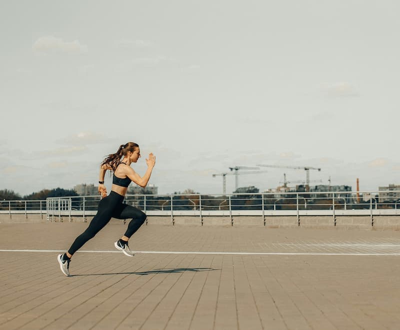 Woman sprinting along a waterfront promenade